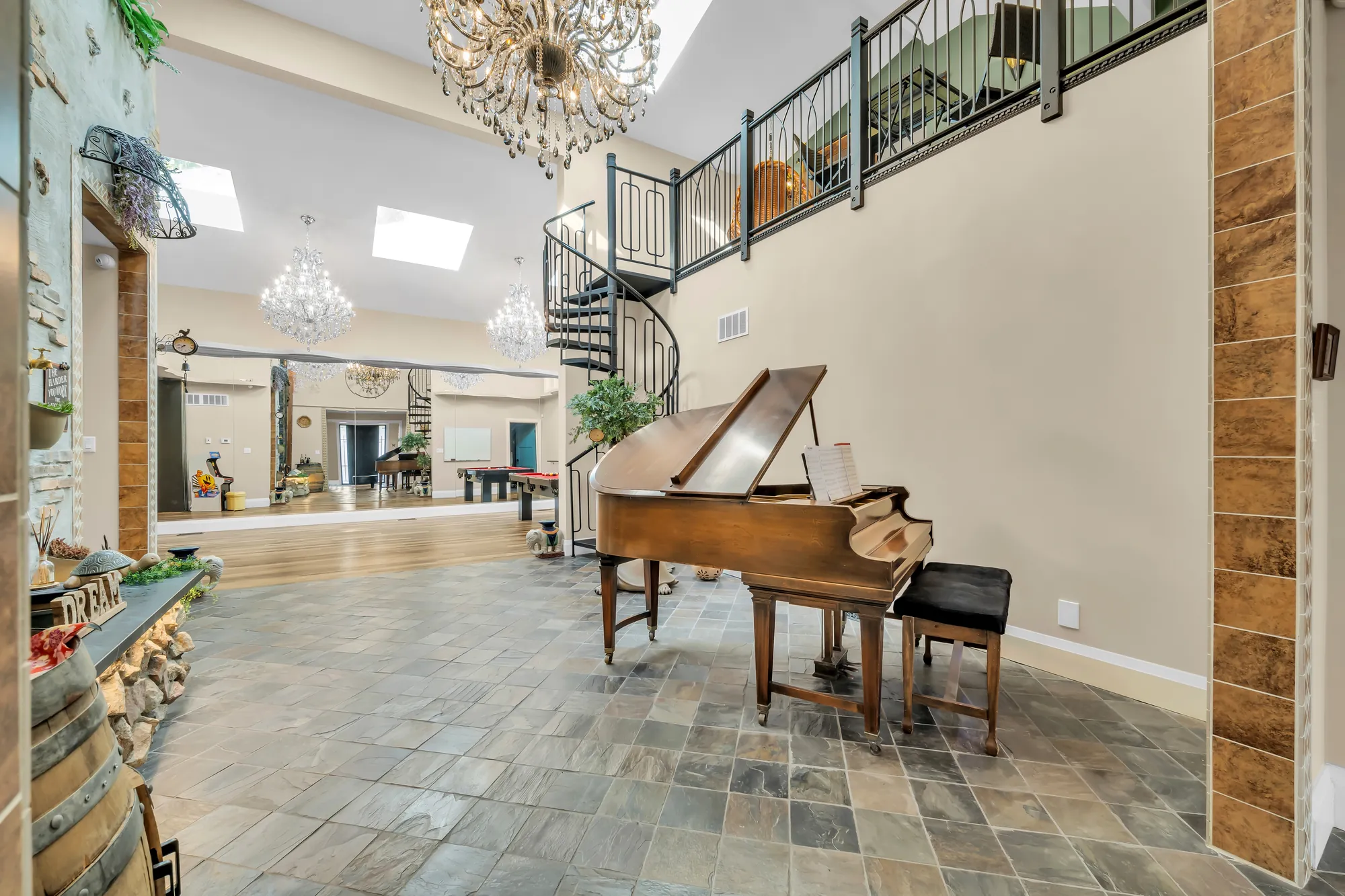 The flex area toward the recreation room: the piano, a wine-barrel bar, a slate floor, the spiral stair