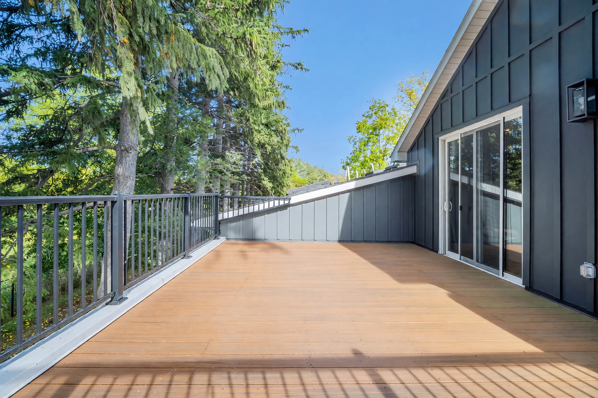 The balcony toward the sliding doors in the dark siding, the railing at the left