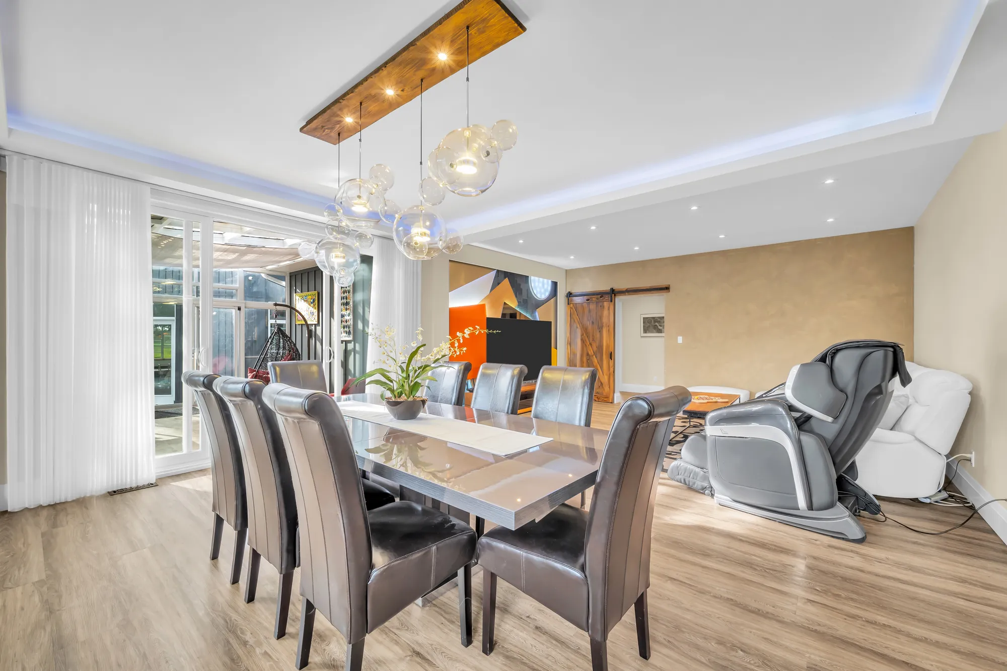 The dining table toward the sunroom, a massage chair and the mural wall at the right
