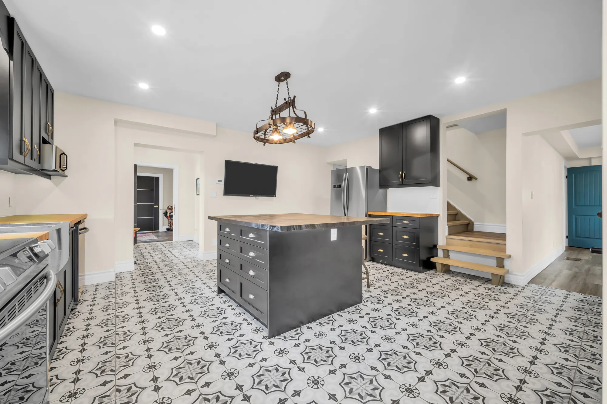 The kitchen toward a stair up and a teal door, the island and the range