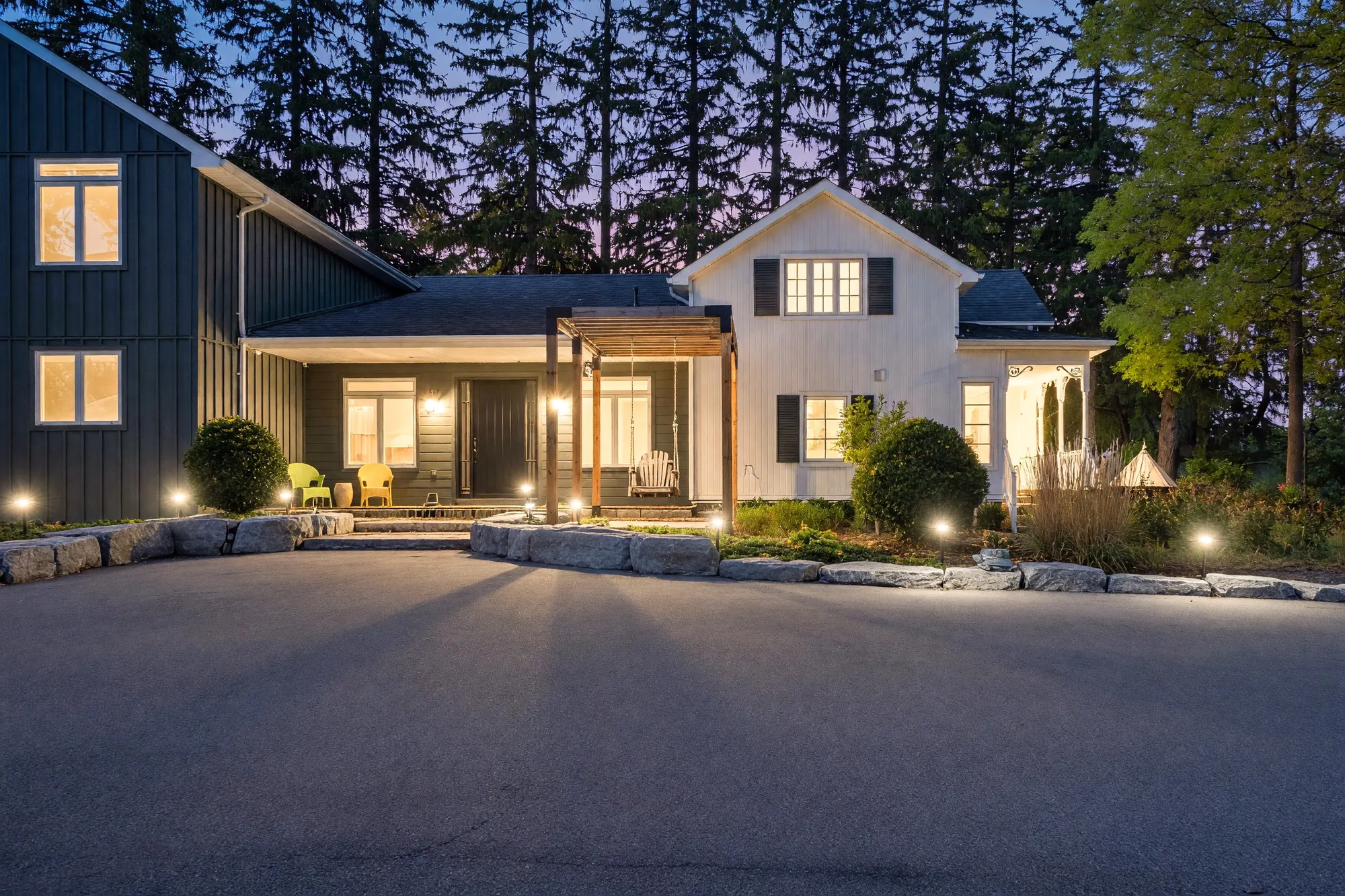 The same view at dusk, the windows, the porch and the side porch lit