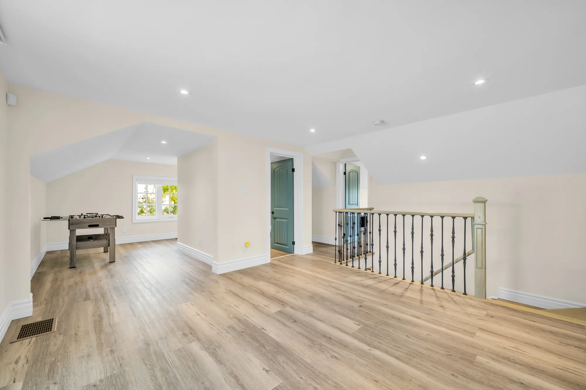 The same room with a foosball table beside the stair railing, a door