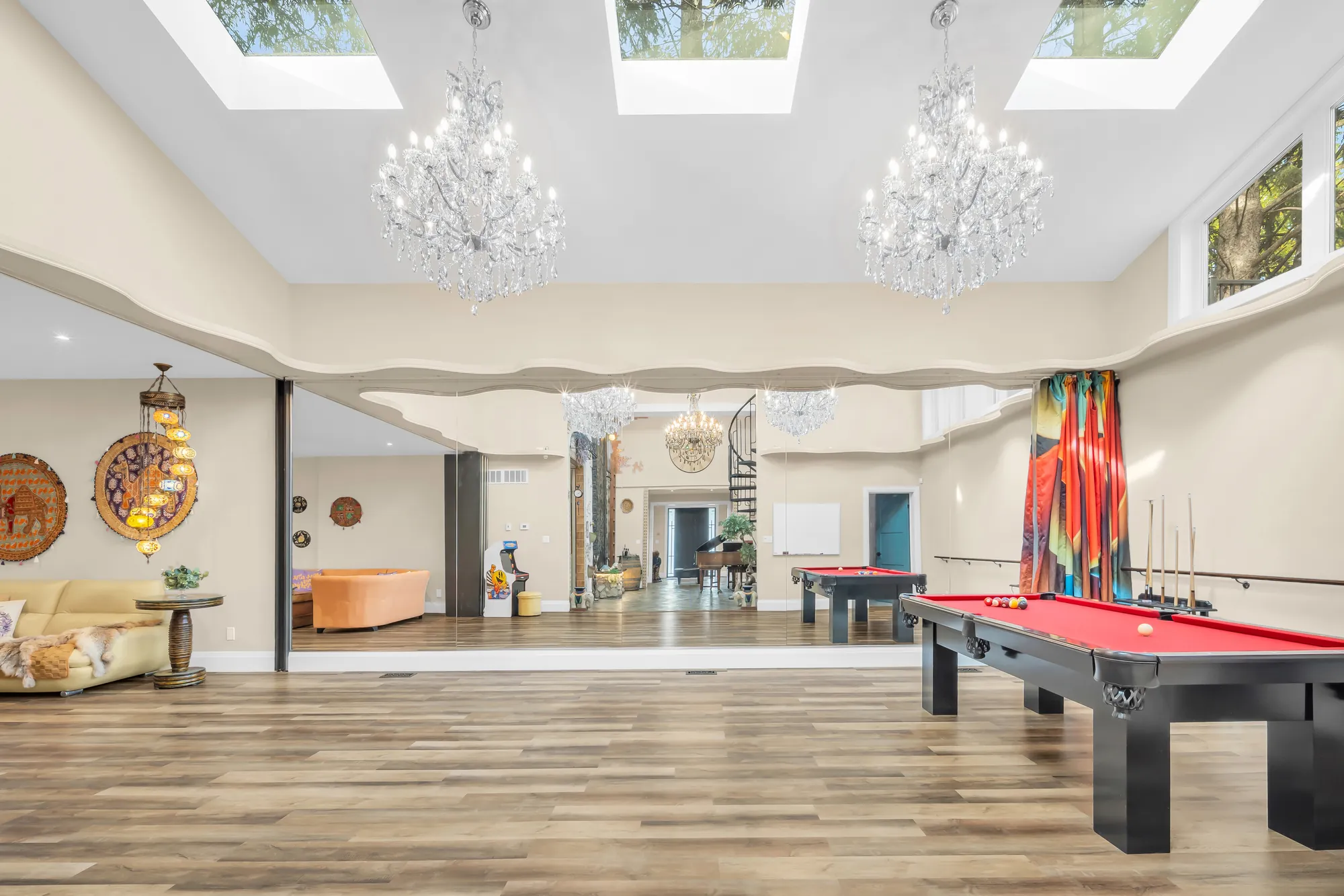 The recreation room: a pool table with red felt, skylights and two crystal chandeliers, a mirrored wall, a striped curtain, the flex area at the far end