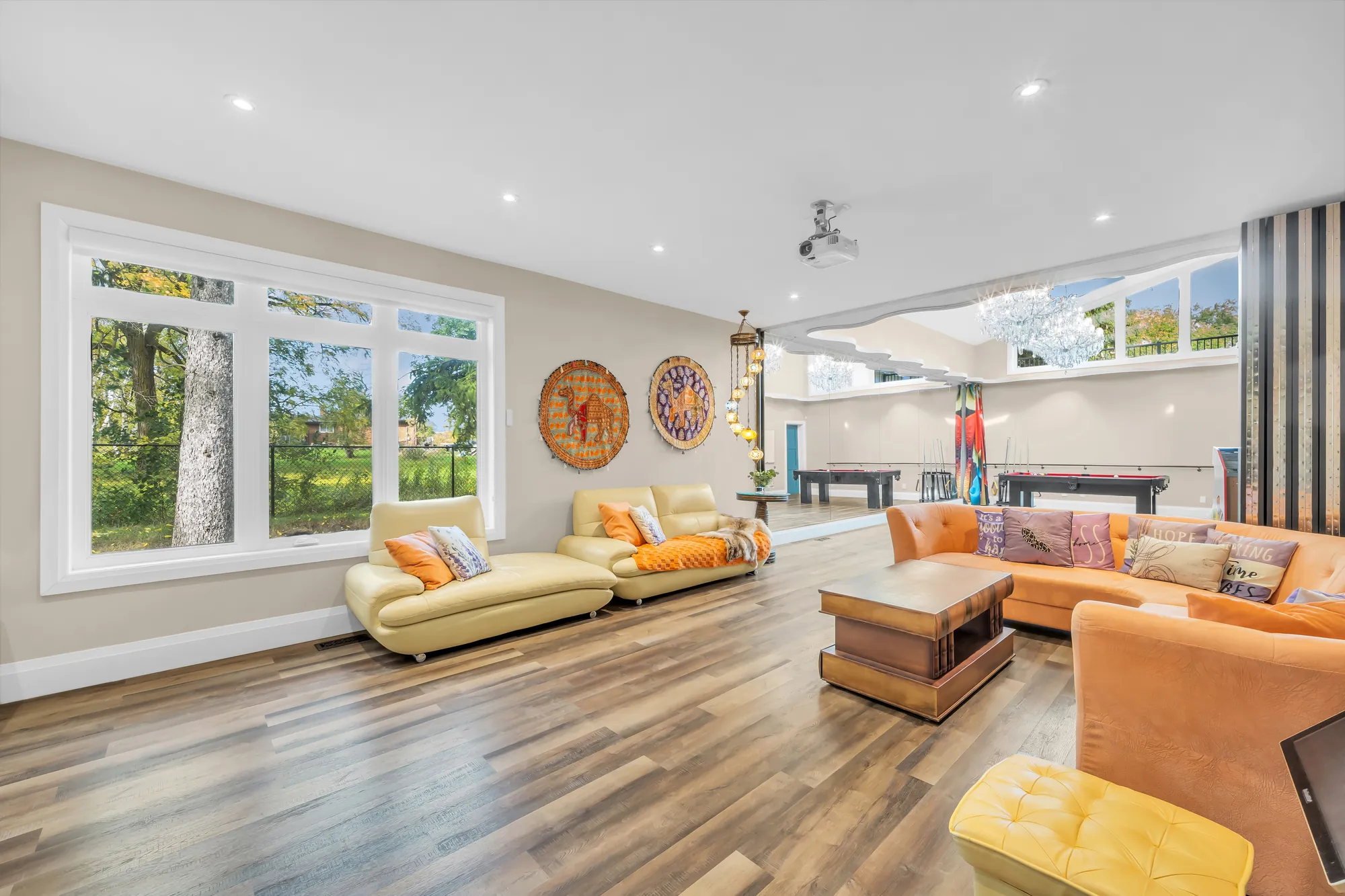 Yellow and orange sofas by wide windows onto the yard, a patterned carpet