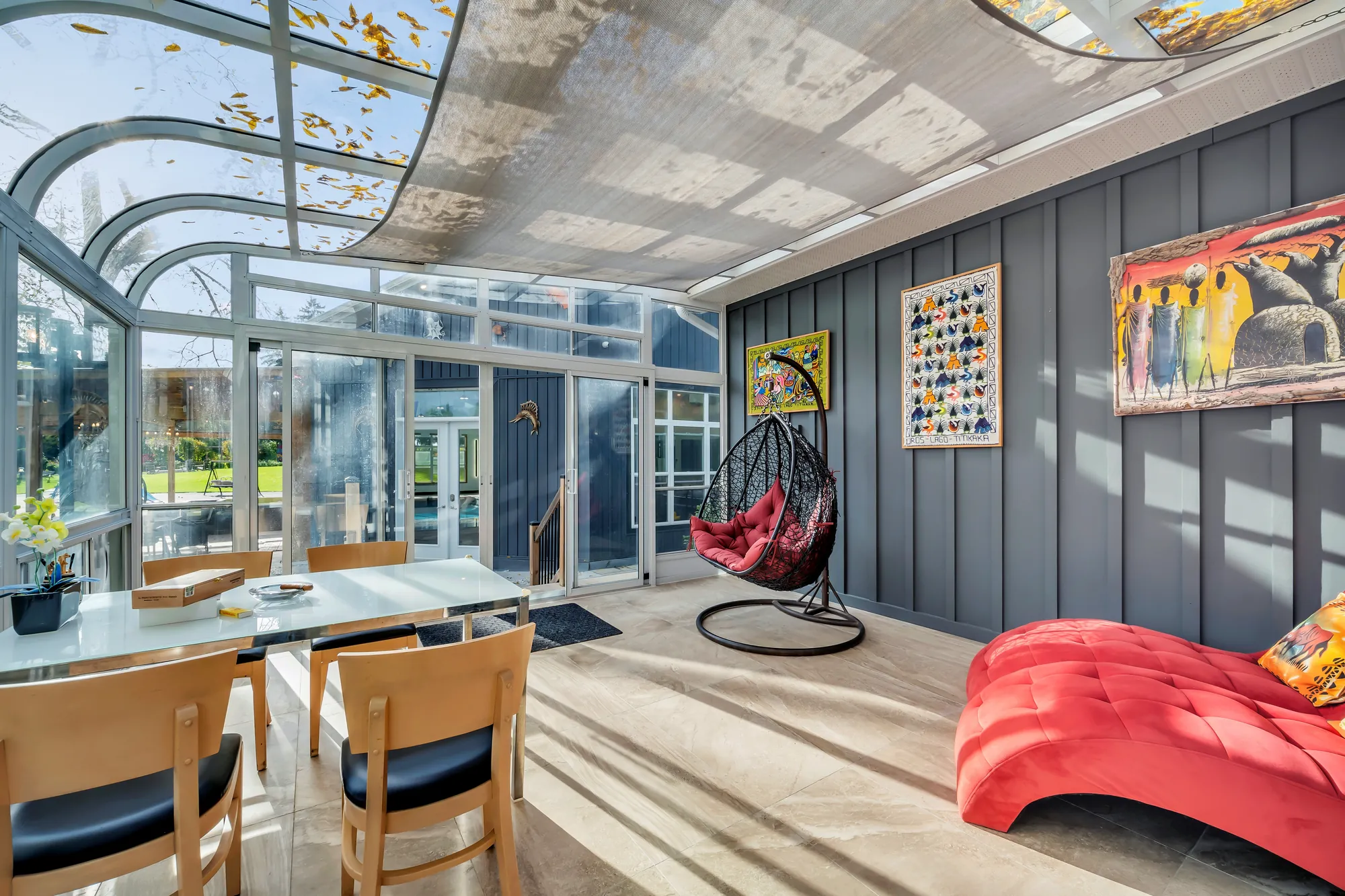 The sunroom from the other side: the glass roof, the dining table, the egg chair and the red chaise