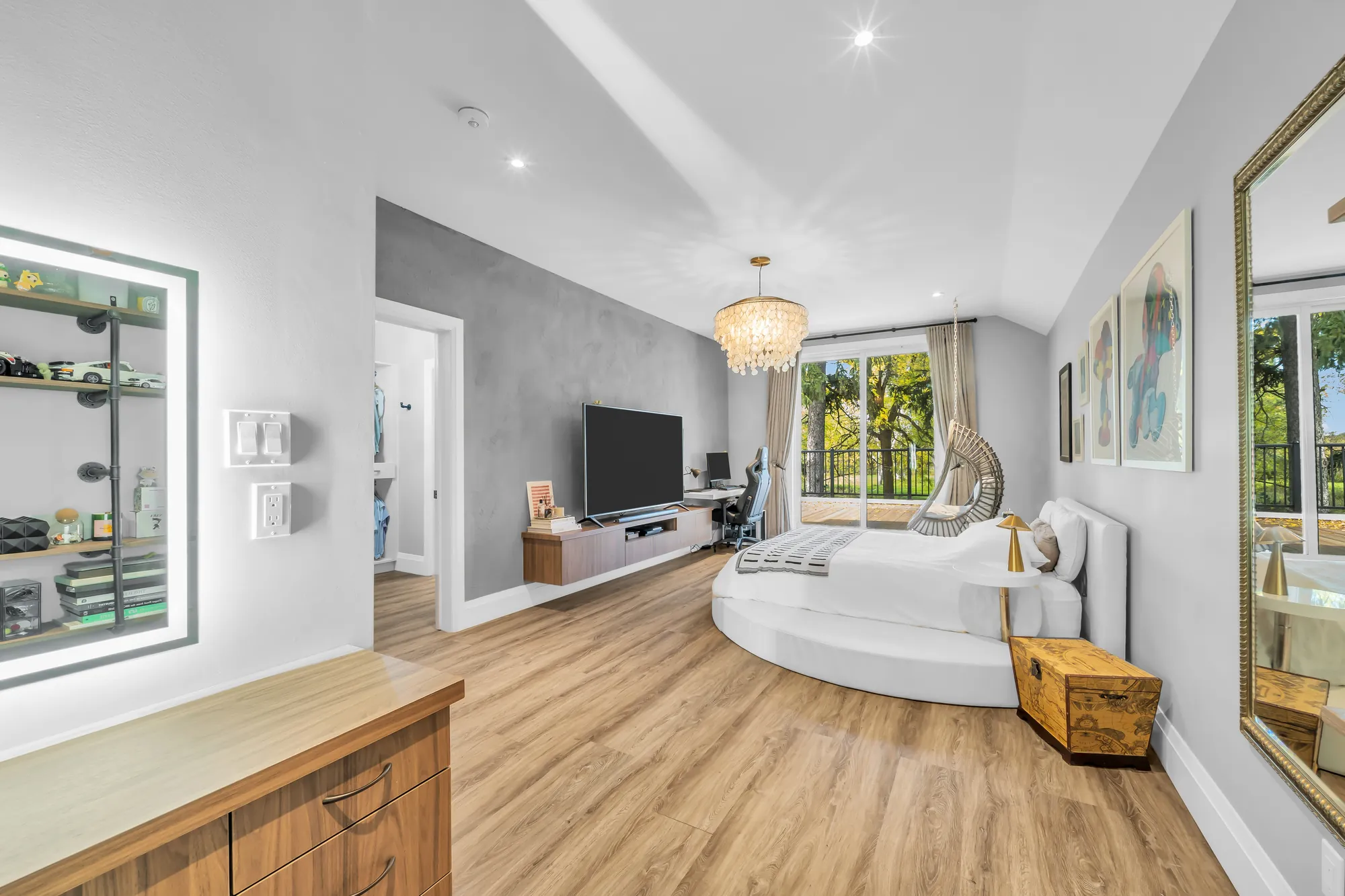The bedroom from the door: a lit mirror and shelves at the left, the round bed, the balcony doors