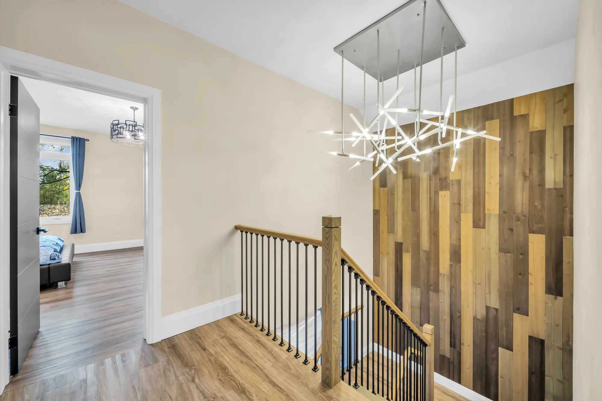 The upstairs hall: the stair railing, a wall of wood planks, a sculptural chandelier, doors to the bedrooms