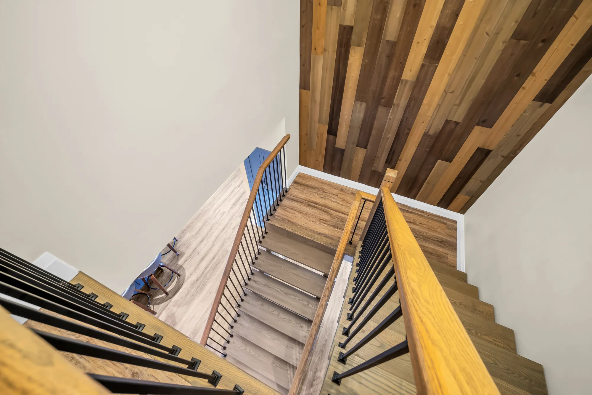 The stair from above: oak treads, black balusters, a wall clad in wood planks